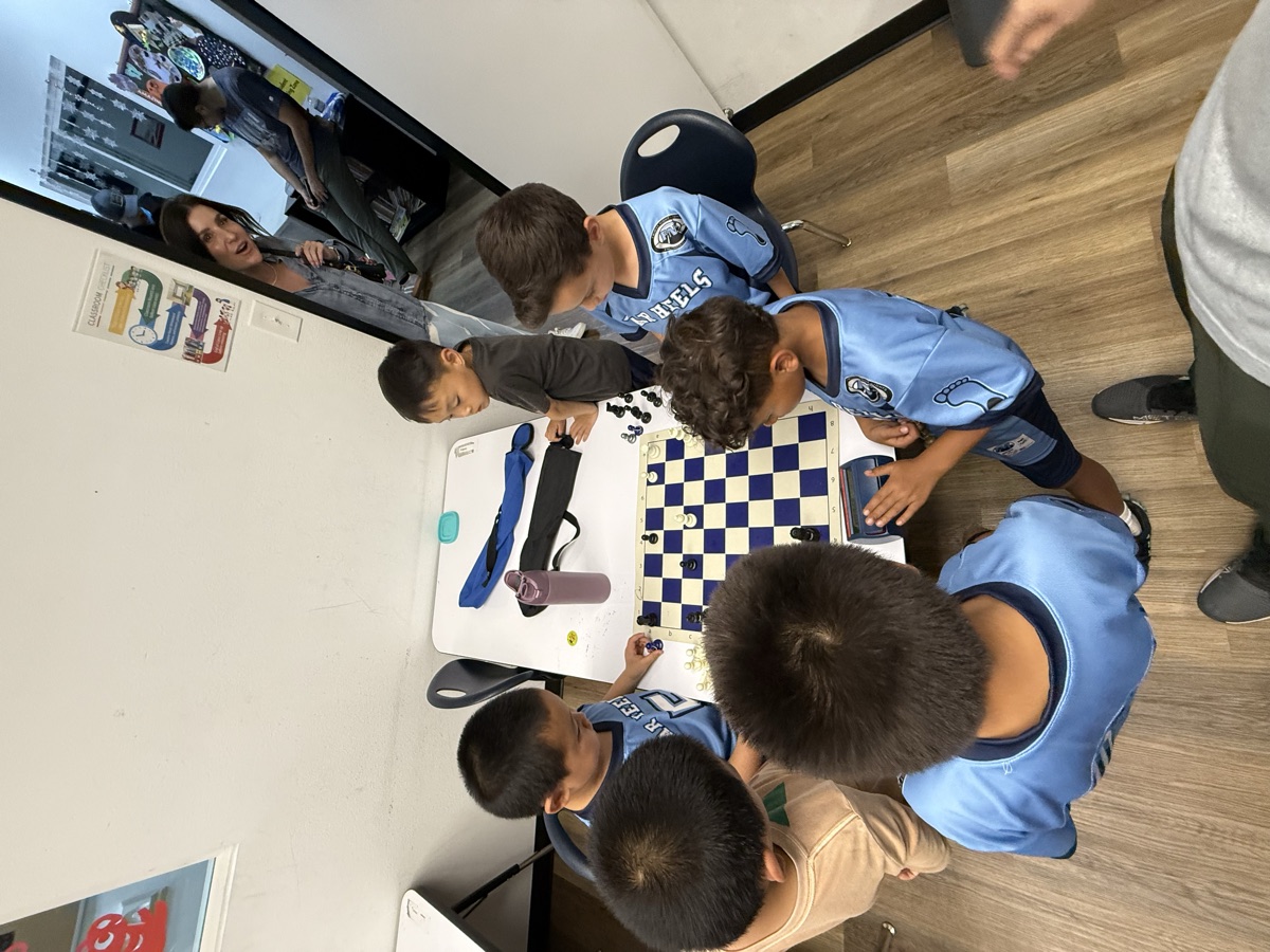 A team of students in matching jerseys gathered around a chess board