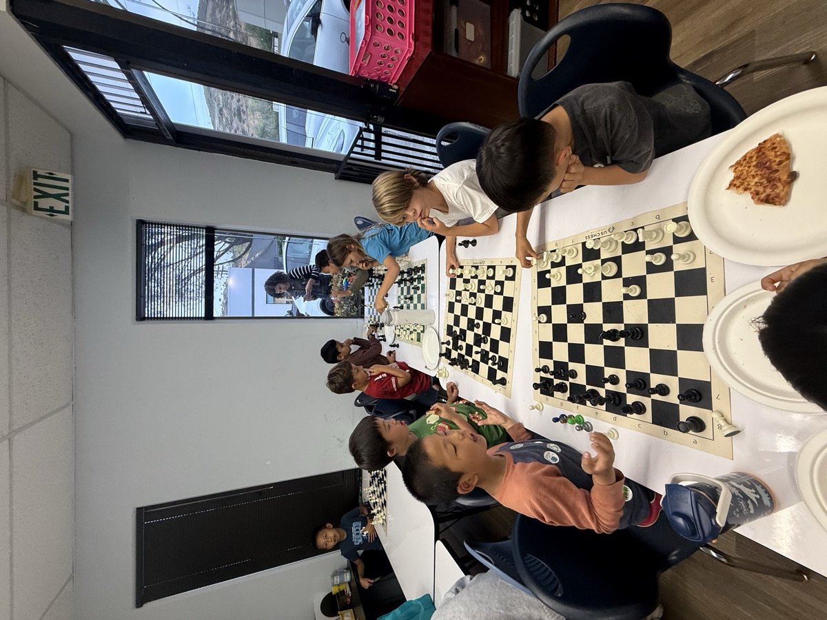 Students playing chess together over pizza