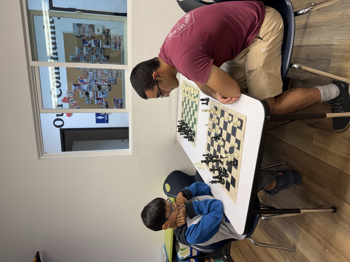 A coach and student playing chess together in the classroom