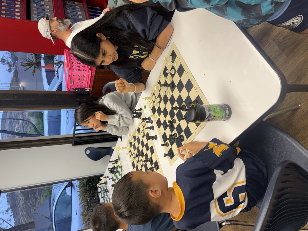 Students and a coach focused on a chess match