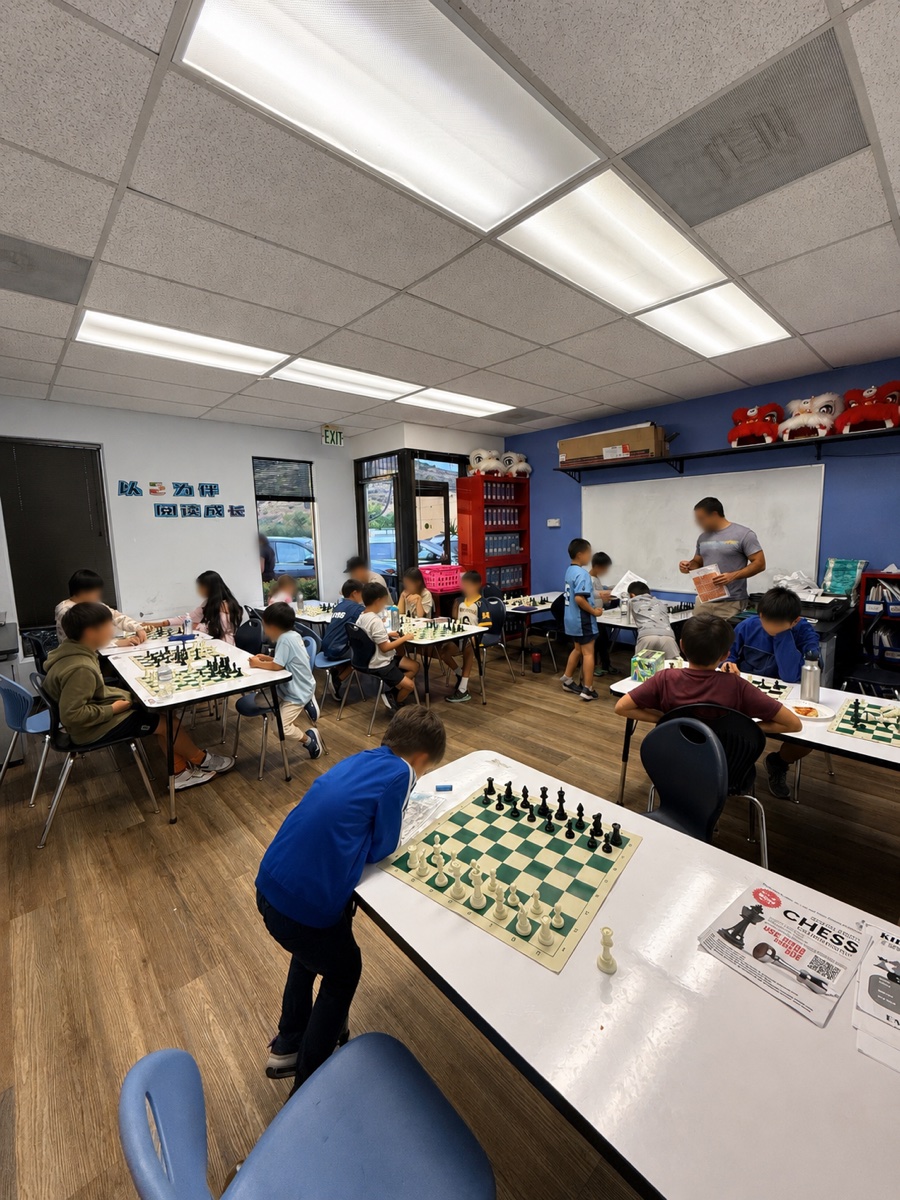Students playing chess together at classroom tables