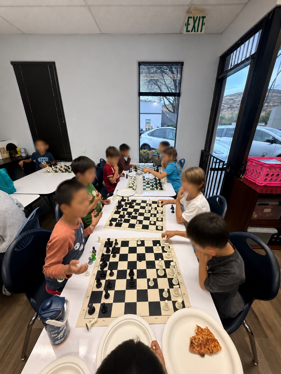 Students gathered around chess boards during class